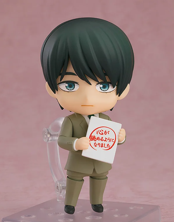 Figure of a man with dark green hair blue eyes and a tan suit holding a white sign with red Japanese text