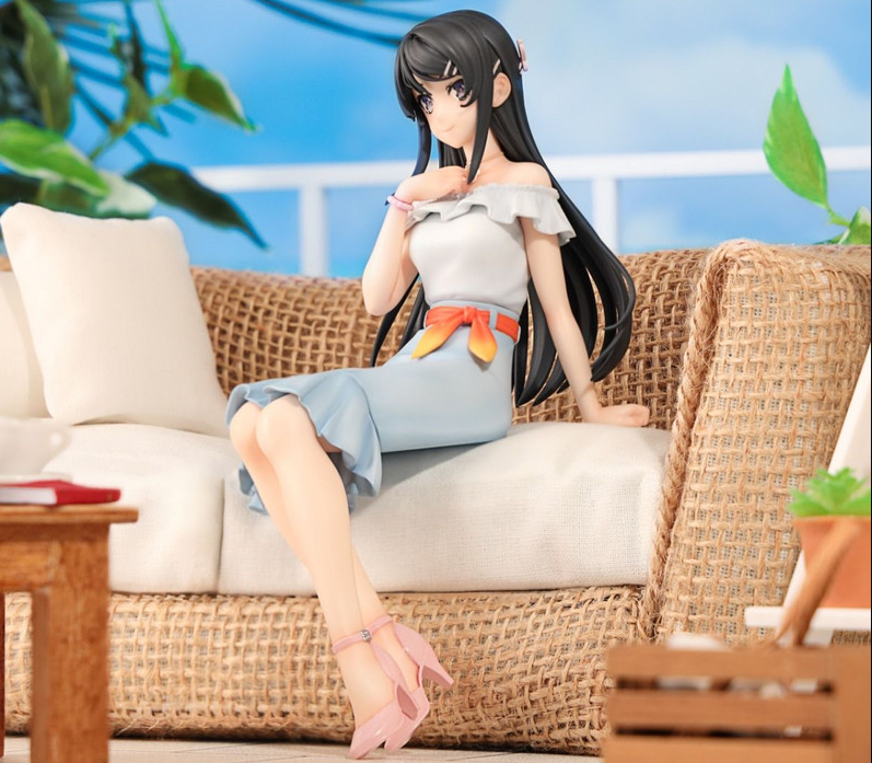 Figure of a woman with long black hair wearing a white top and light blue skirt sitting on a woven sofa