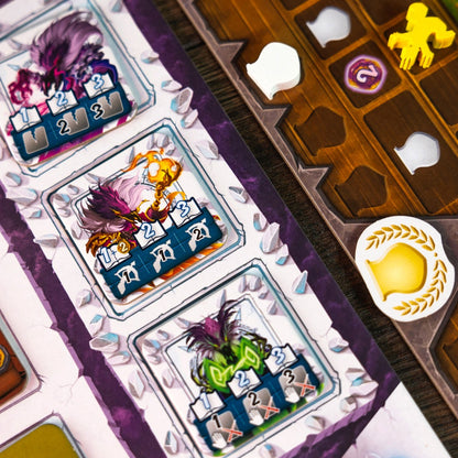 Close up of three colorful fantasy creature game tokens with numerical value tiles on a tabletop game board