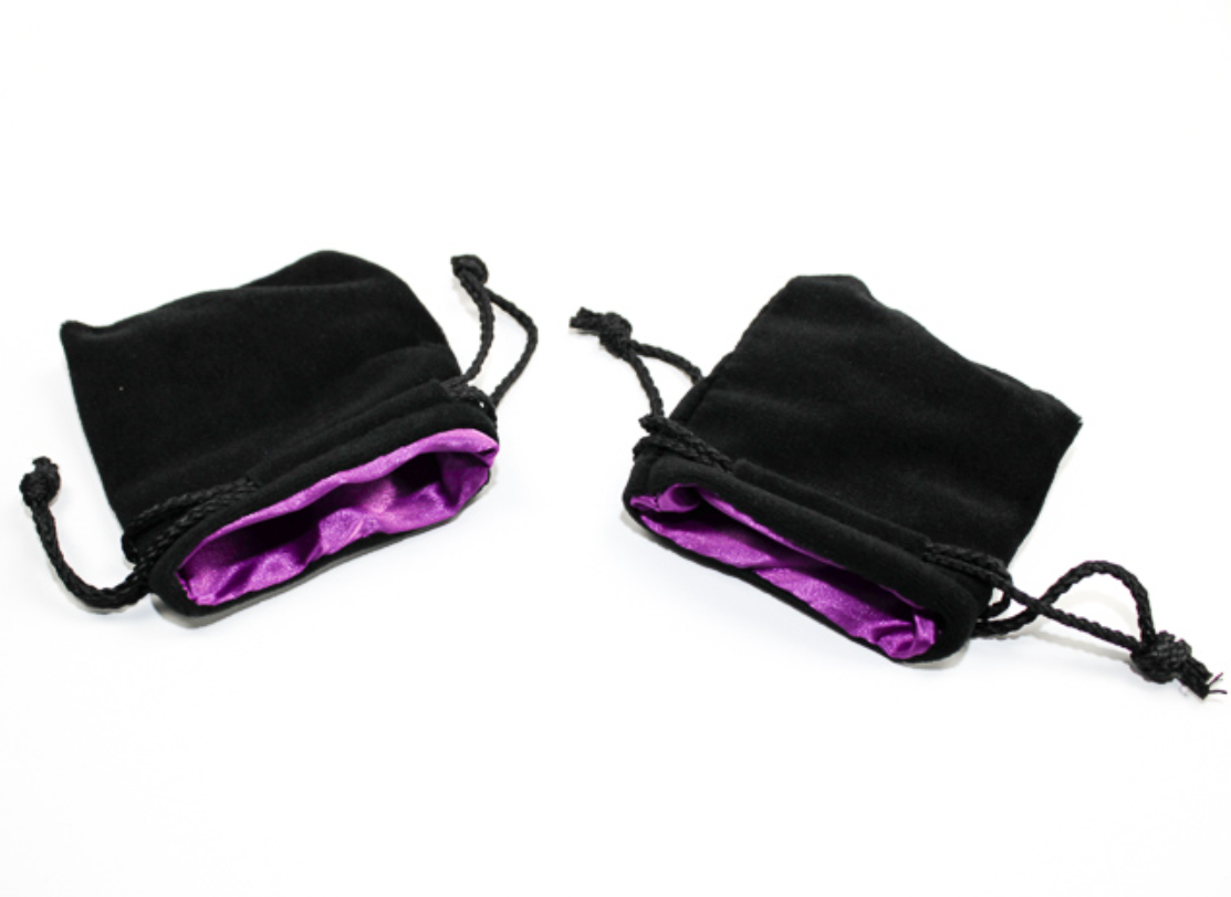 Chessex Velvet 3.75 Inch X 4 Inch Black Purple Dice Bag with vibrant purple satin lining lie on a white surface