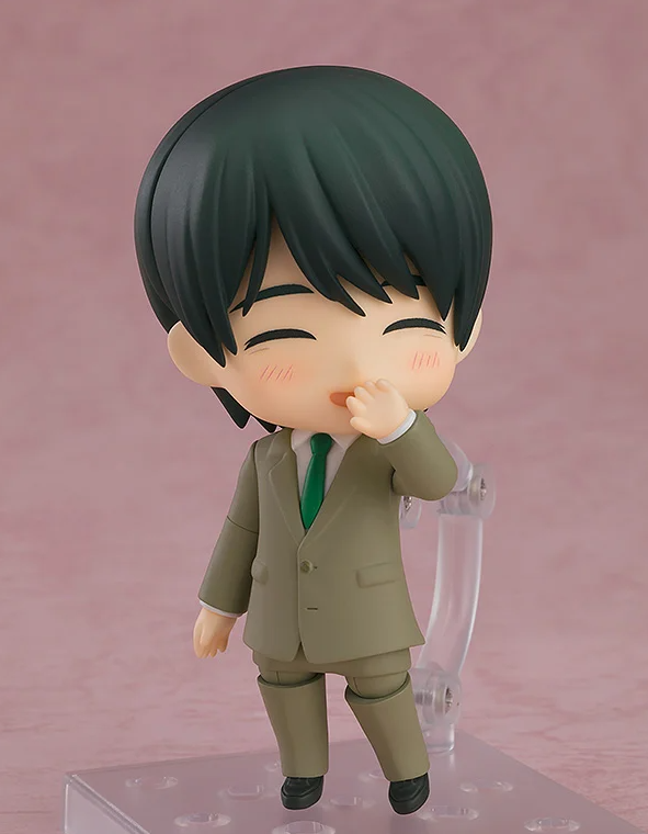 Figure of a man in a tan suit and green tie covering his mouth with one hand and smiling