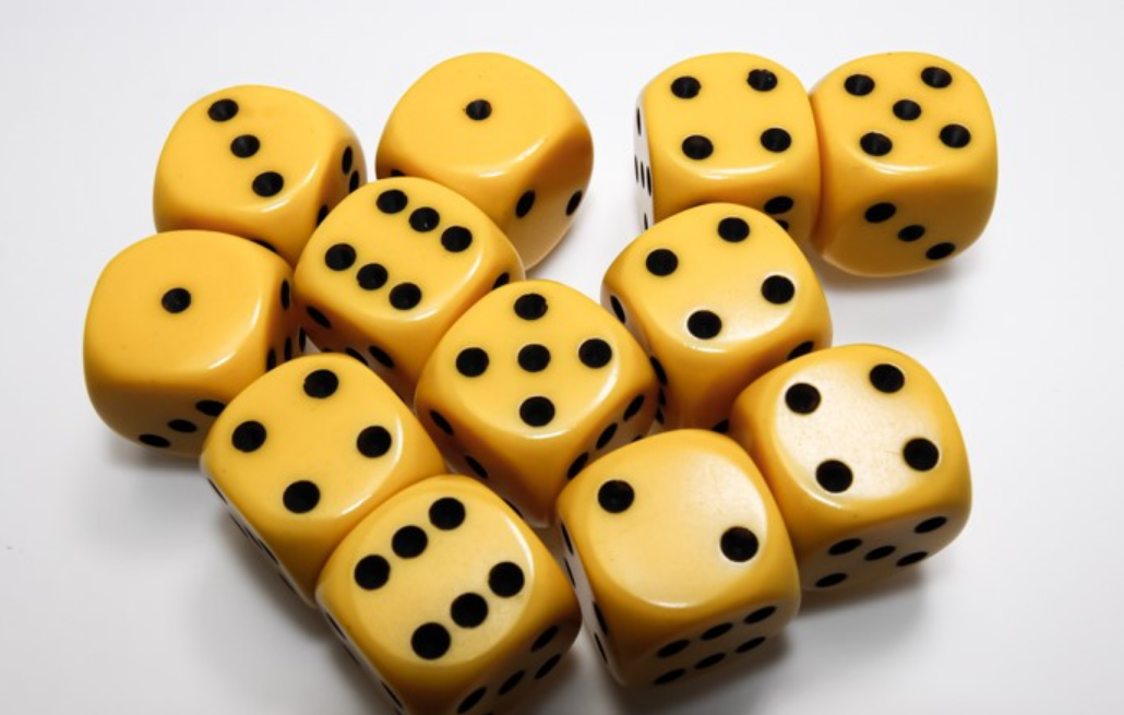 Numerous yellow-colored dice with black pips resting on a white surface