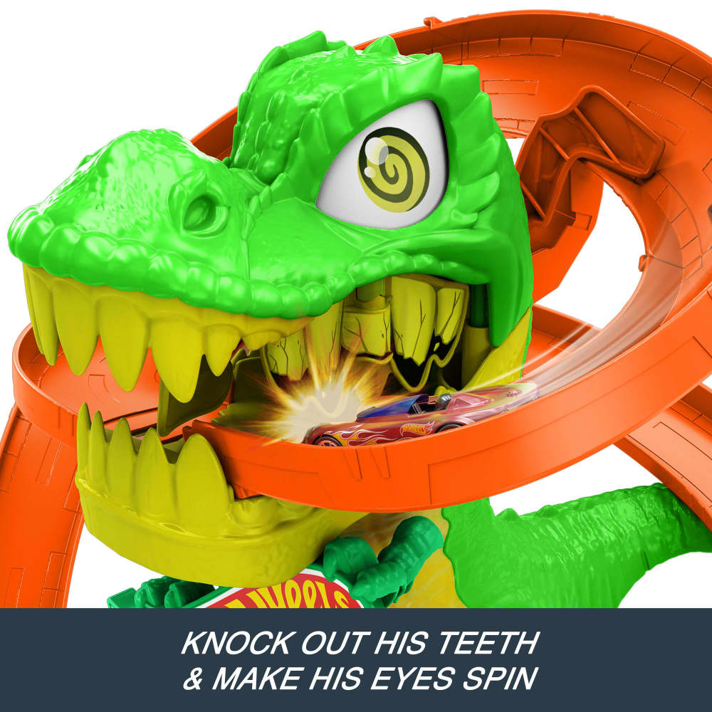 Two Hot Wheels cars race through a green dinosaur's mouth, striking yellow teeth on an orange track