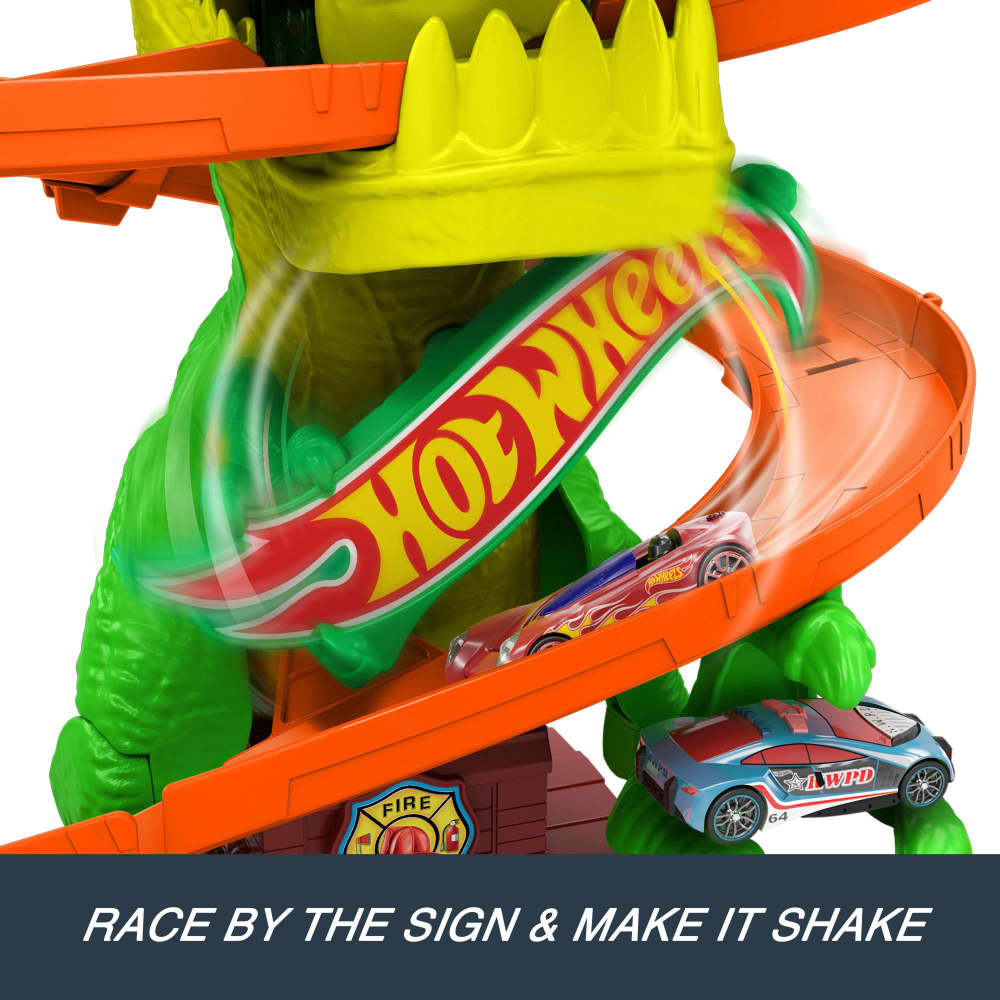 A red Hot Wheels car speeds past a spinning logo in a green monster's mouth on an orange track loop. A blue car waits below
