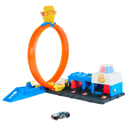 A Hot Wheels playset with an orange loop track, a blue launcher, a police station building, and a black toy car