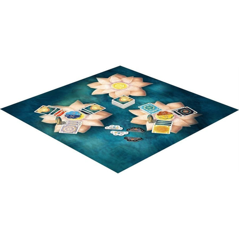 Board game setup featuring lotus-shaped play areas with cards and tokens on a teal background