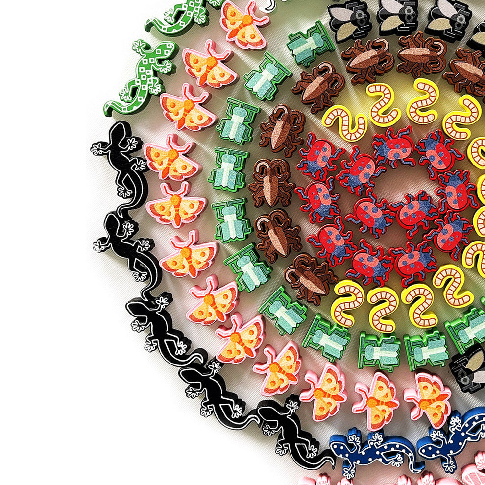Colorful small animal and insect buttons, including lizards, moths, and ladybugs, arranged in a large spiral