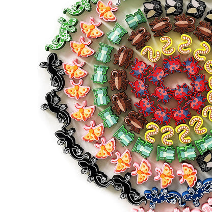 Colorful small animal and insect buttons, including lizards, moths, and ladybugs, arranged in a large spiral