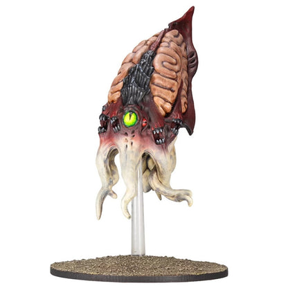 Grotesque miniature creature with exposed brain, large glowing green eye, fanged mouths, & pale tentacles on base