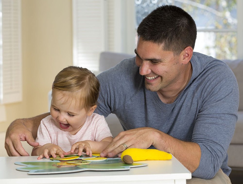 Dad and baby laugh playing Monkey Around game, yellow banana toy on table