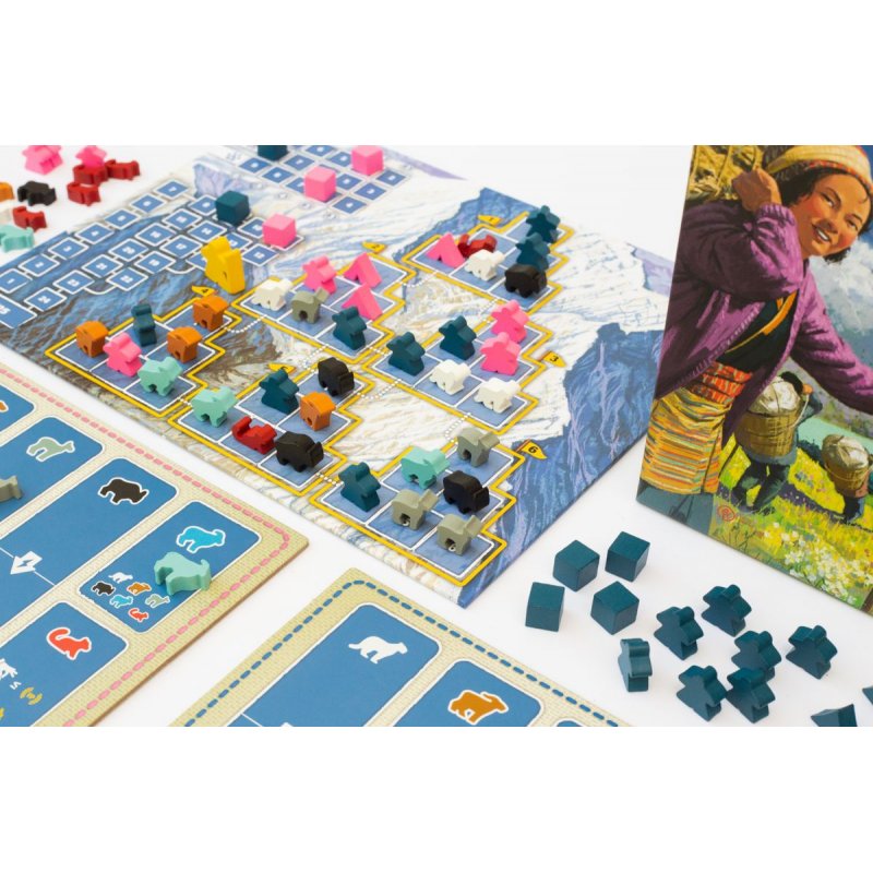 Nanga Parbat board game components: wooden animal pieces on a mountain map board, player mats, and a box with a smiling woman