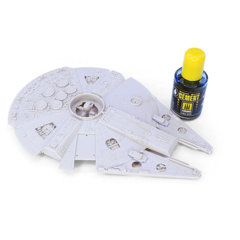 Unassembled gray plastic Millennium Falcon model kit pieces with a bottle of model cement