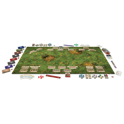 Overhead view: A strategic tabletop wargame fully set up on a green terrain mat, featuring army units, cards, and dice.