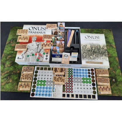 ONUS! TRAIANUS historical wargame components: boxes, rulebooks, unit cards, and tokens spread on a green battlemat.