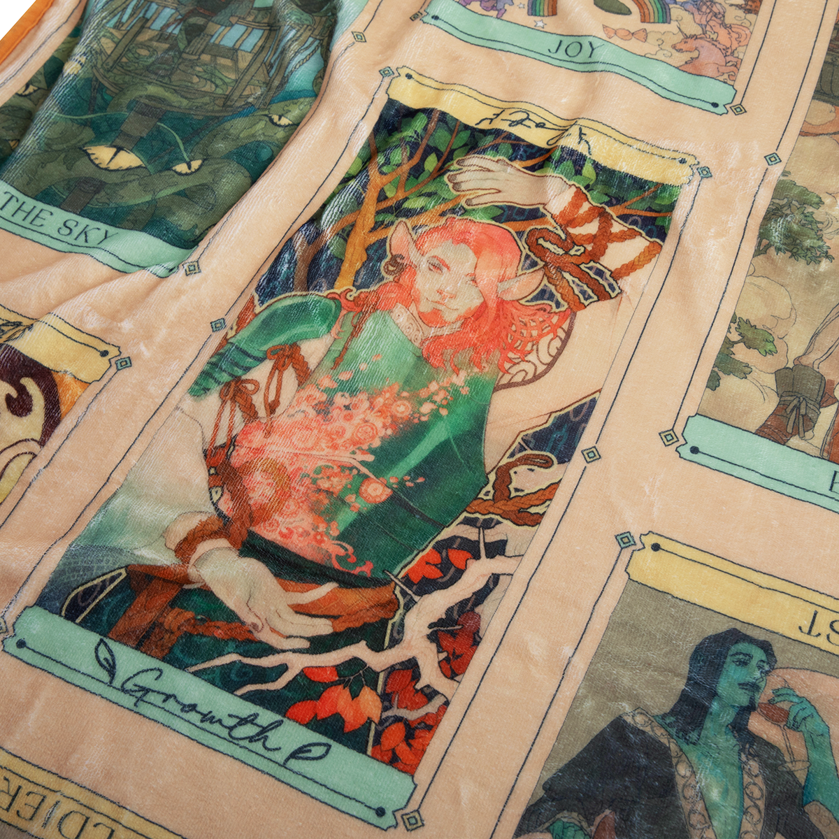 Colourful fantasy art racle of the Moon Tarot Blanket featuring tarot-like cards. A red-haired, pointed-eared figure on the central 'Growth' card