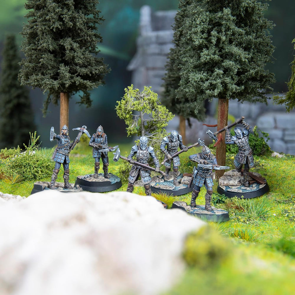 Six fantasy-style armored miniature figures wielding pickaxes, hammers, and crossbows in a forest setting with ruins.