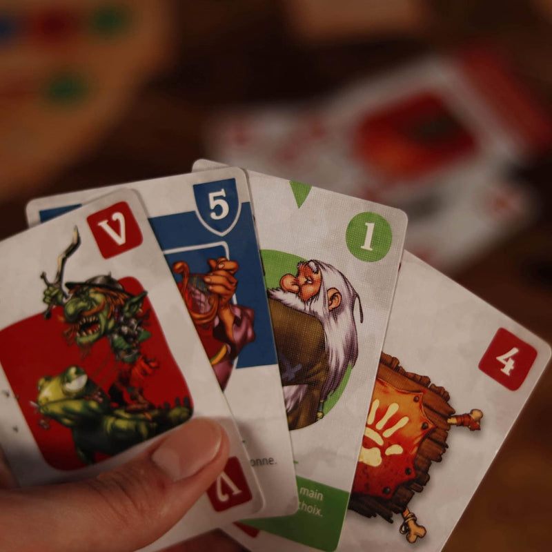Hand holding four playing cards with illustrated fantasy characters including a green goblin a dwarf and a wooden creature