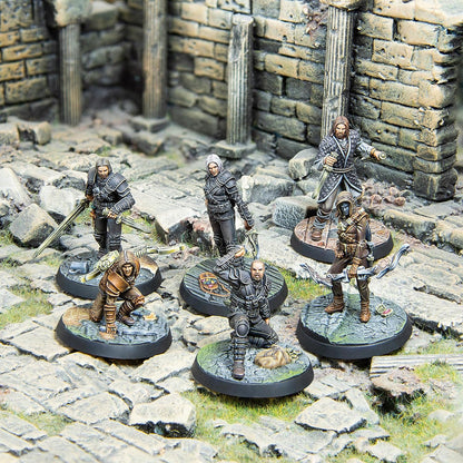 Six fantasy warrior miniatures, armed with swords and bows, standing and crouching amidst stone ruins.
