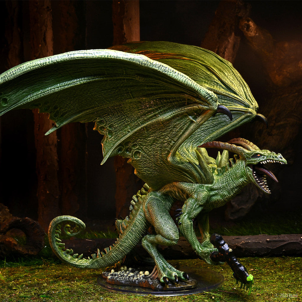 Green dragon miniature roars, wings out, holding a staff, on a mossy forest base