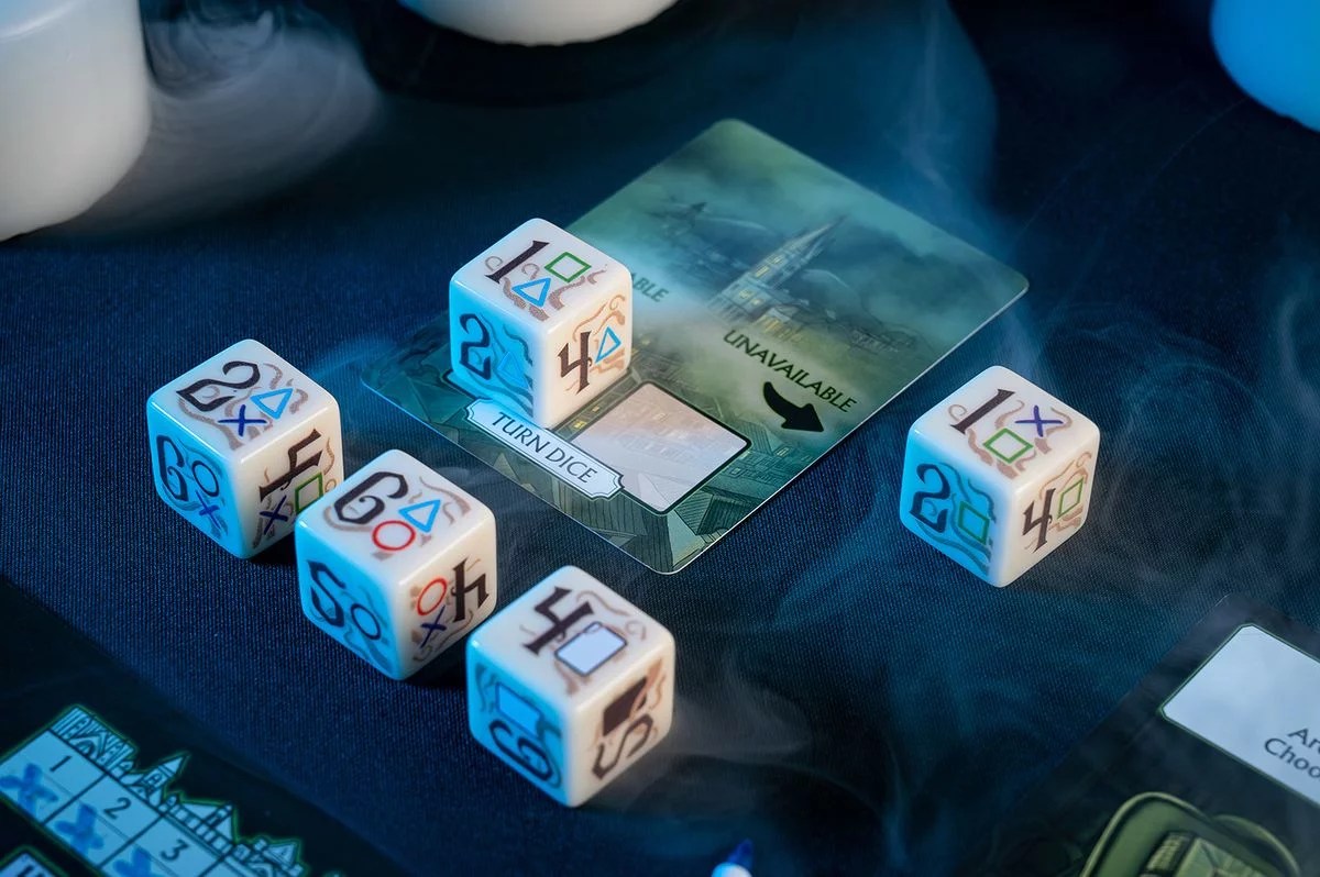 Five white board game dice with numbers and symbols (PlayStation-style) on a dark blue surface, next to a game card in smoke