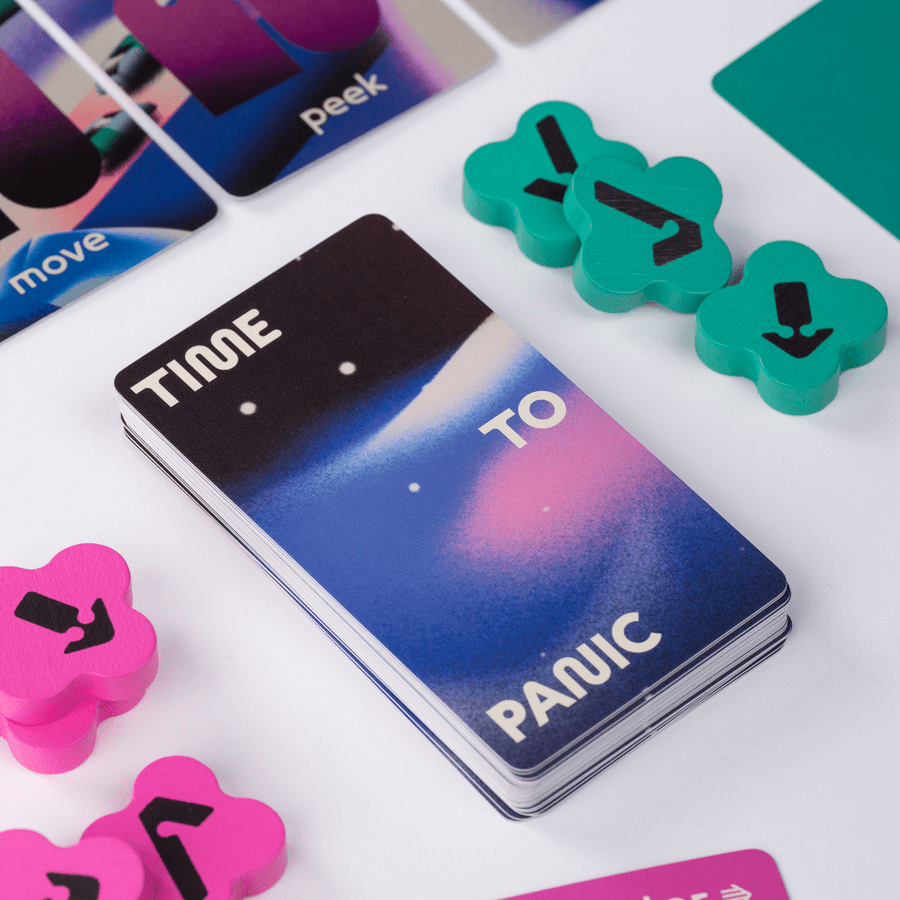 Stack of "TIME TO PANIC" cards surrounded by colourful wooden directional tokens and other game cards