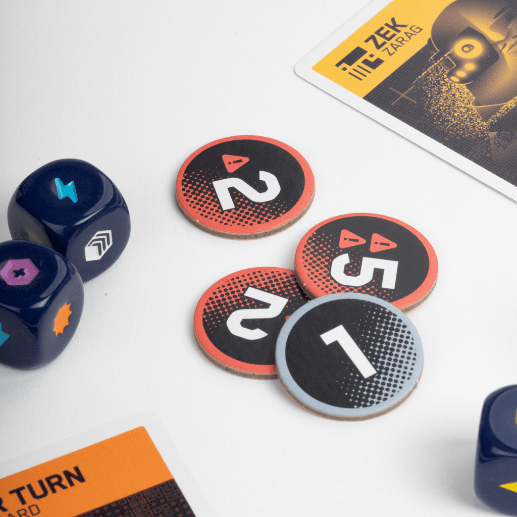 Numbered board game tokens and dark blue dice laid on a white surface with game cards