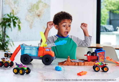 Excited boy playing with a Hot Wheels Monster Truck Transporter and a crushing playset with smaller monster trucks