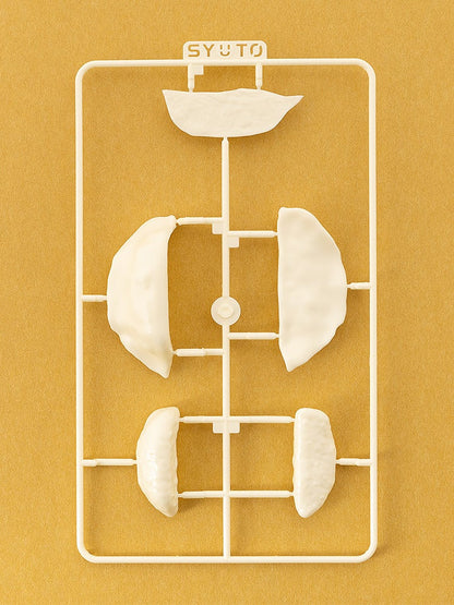 White plastic model kit sprue with various dumpling and pasta shapes, on a yellow background