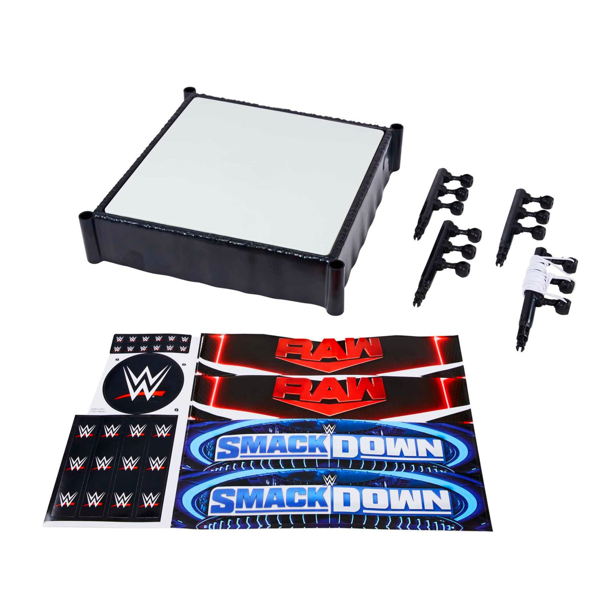 Disassembled WWE wrestling ring playset: white ring mat, black corner posts with ropes, and Raw/SmackDown logo stickers