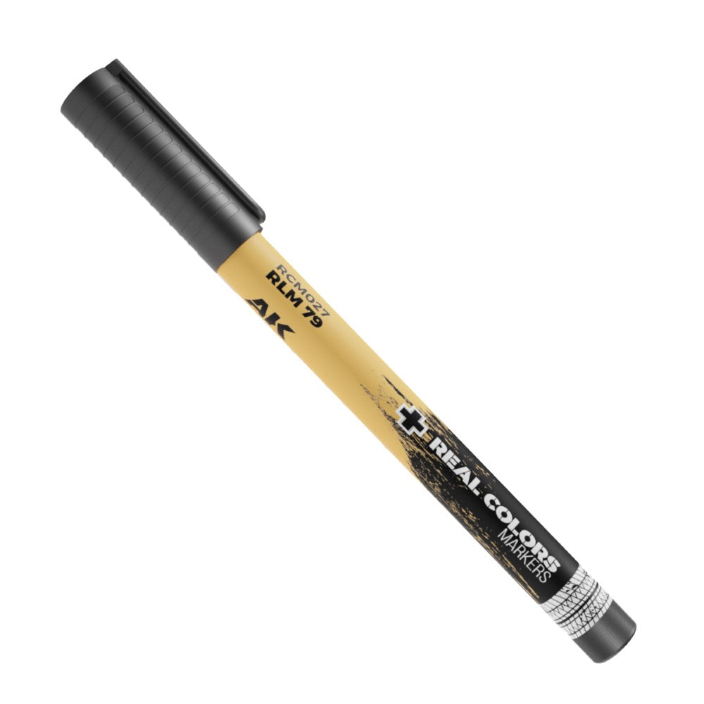 A tan AK Real Colors marker with a black cap, showing RCM027 RLM 79 text and a black splatter design
