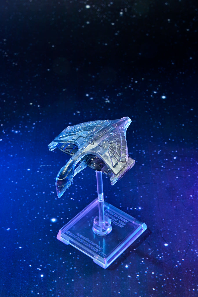 Translucent futuristic spaceship model on a clear stand, illuminated with blue and purple light against a starry background