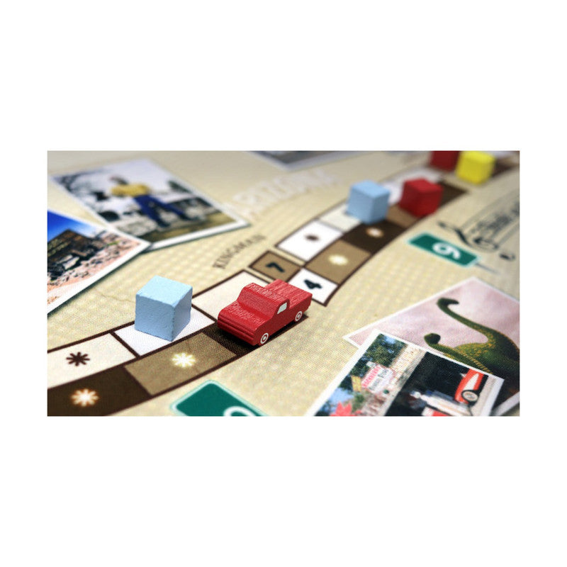 Colorful board game with small blue cubes and red car piece on a detailed map layout