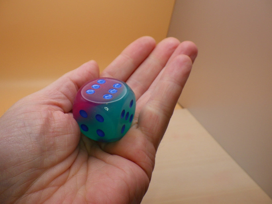 Gel Green Pink and Blue Luminary die showing six blue pips held in a hand   