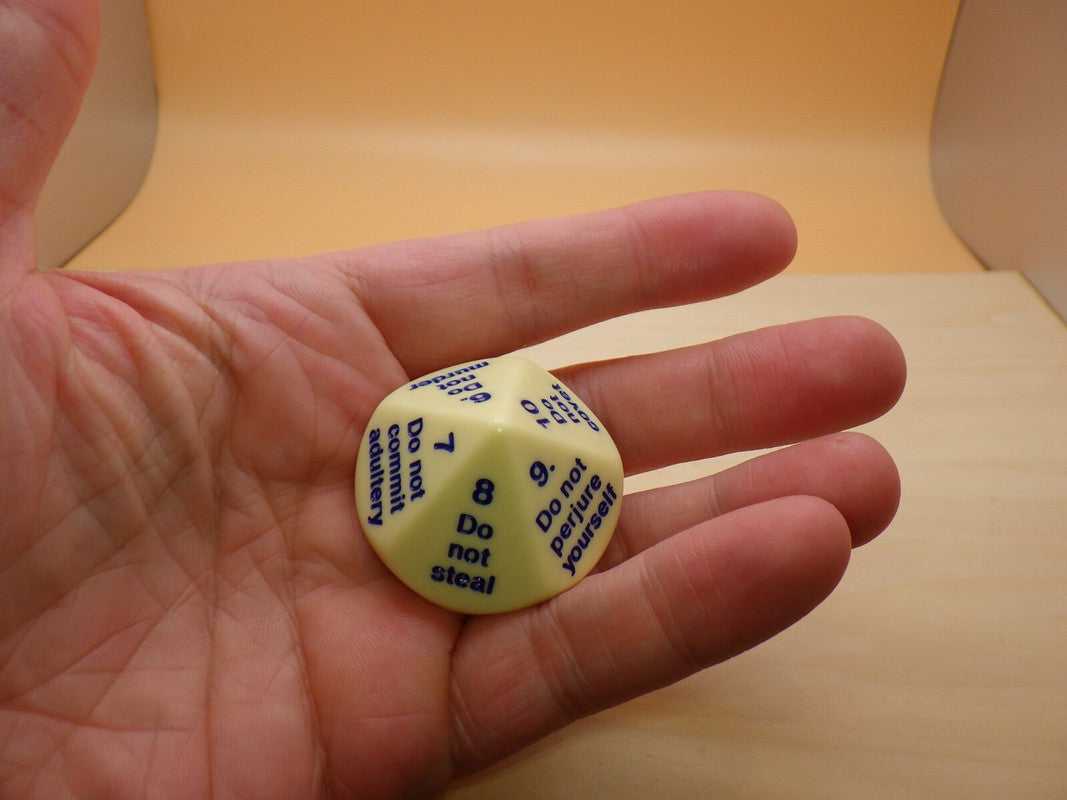 Hand holding a pale yellow 12-sided Ten Commandments die 