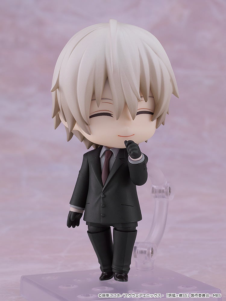 White-haired Nendoroid figure in a dark suit, smiling thoughtfully with a gloved hand on its chin.