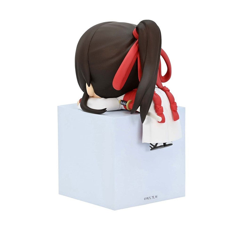Chibi-style figure of a person with dark hair tied in pigtails with red ribbons wearing a white and red outfit and sitting on a white cube