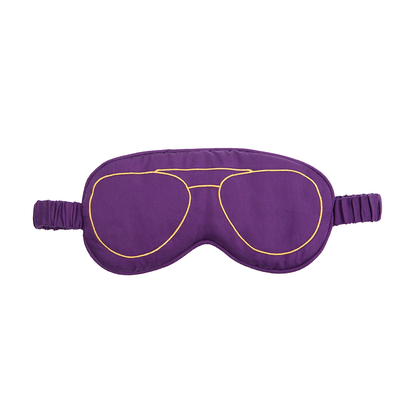 A purple sleep mask with a gold embroidered aviator sunglasses outline