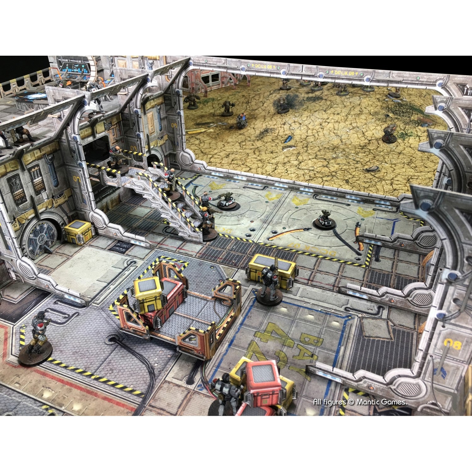 Miniature soldiers battle in a multi-level sci-fi wargame terrain with a desert area beyond.