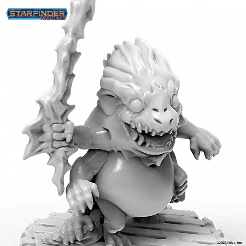 Unpainted Starfinder Skittermander miniature of a grinning, squat, dragon-like monster with big eyes, holding a jagged staff