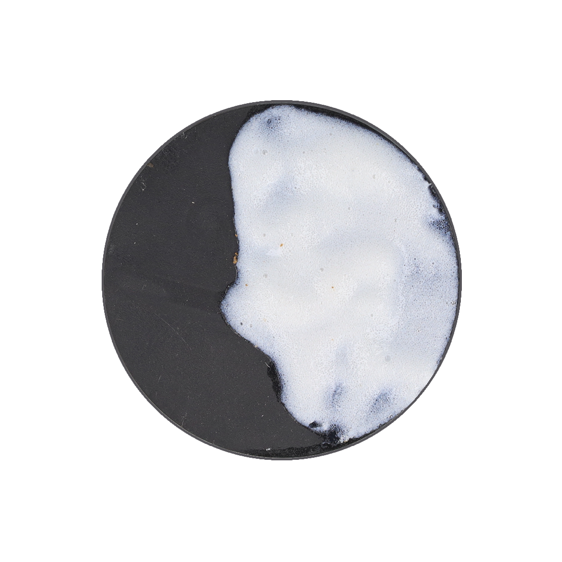 A black circular surface with a large, irregular patch of white, frothy foam covering about half.