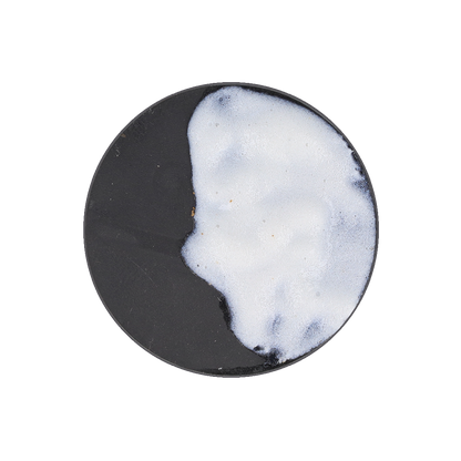 A black circular surface with a large, irregular patch of white, frothy foam covering about half.