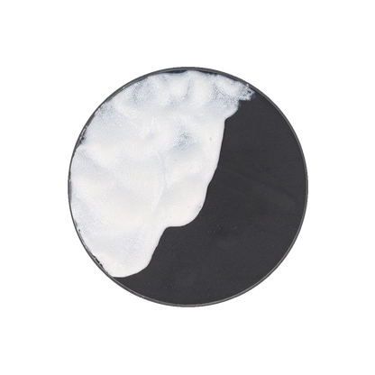 A black circular dish partially covered with white, bubbly foam.