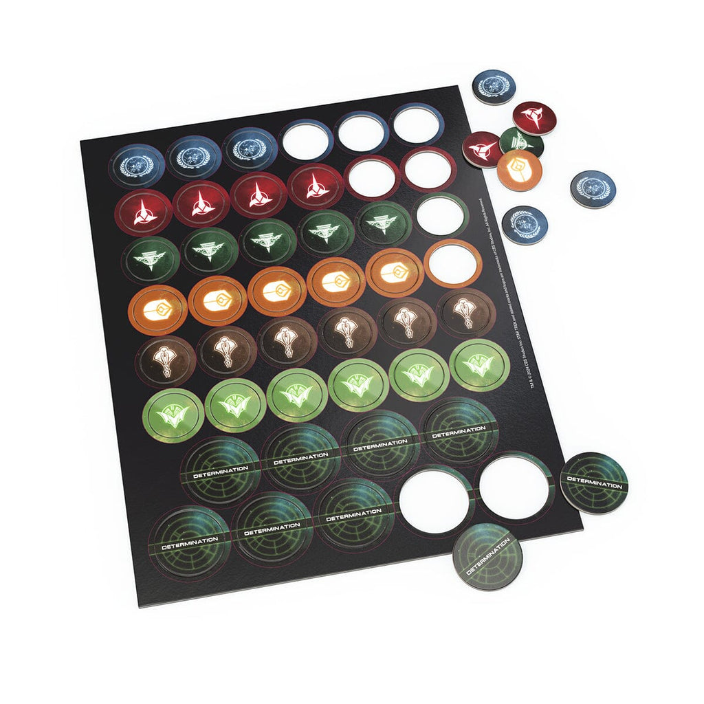 Black punchboard with Star Trek game tokens: blue, red, green, orange faction symbols, and 'DETERMINATION' tokens. Some tokens are loose