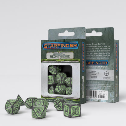 Two boxes for the Starfinder Against The Aeon Throne Dice Set stand behind a scattering of gray and green gaming dice