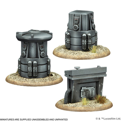 Three grey sci-fi terrain miniatures, including cylindrical and rectangular structures, on desert bases