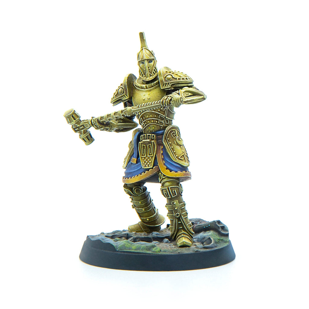 A miniature gold-armored warrior with blue trim, holding a large two-handed hammer