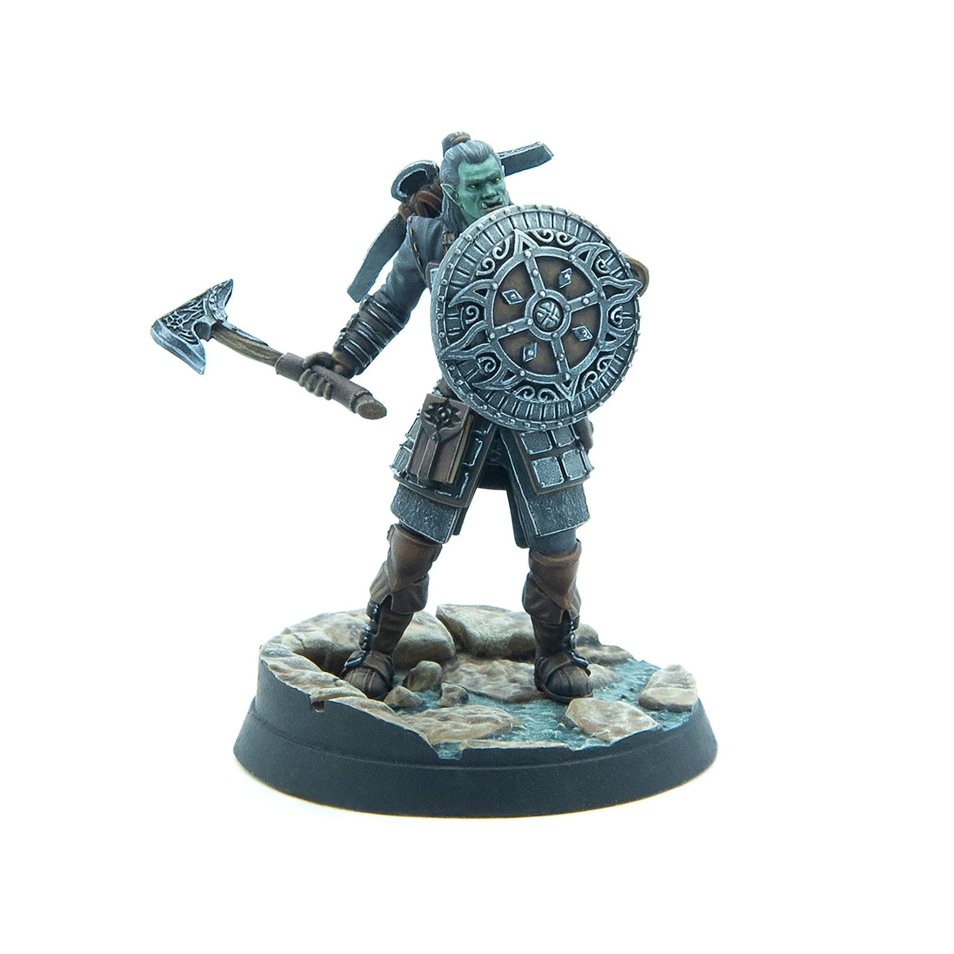 A green-skinned orc warrior miniature with an axe and ornate shield, standing on a rocky base