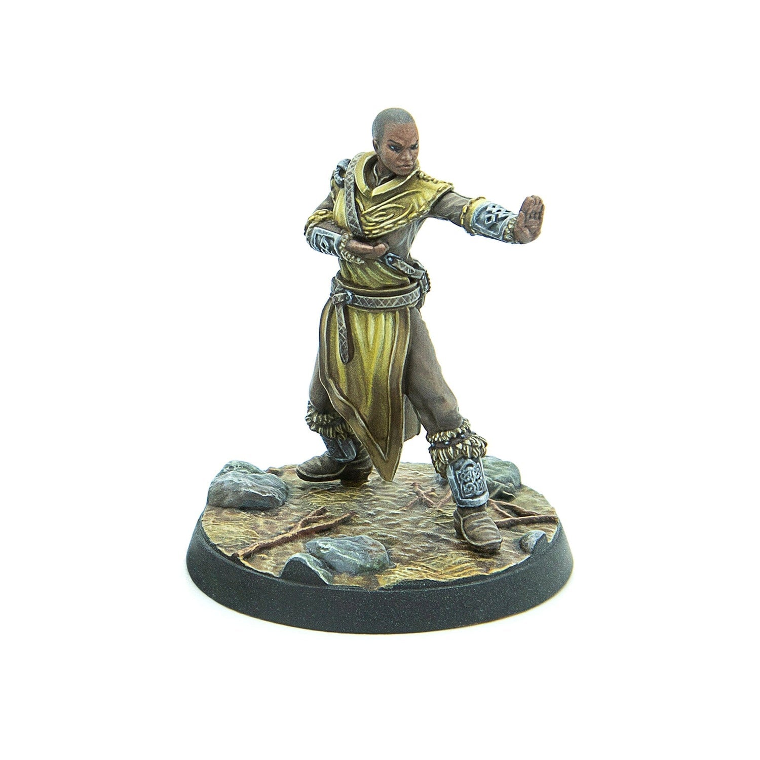 A painted miniature of a bald woman in golden robes, striking a martial arts pose on a rocky base