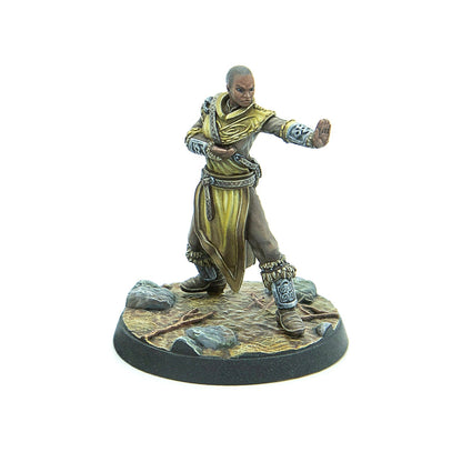 A painted miniature of a bald woman in golden robes, striking a martial arts pose on a rocky base