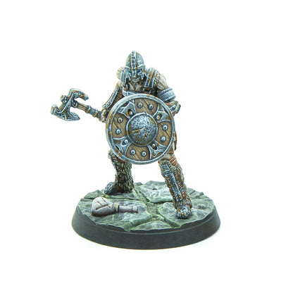 A detailed miniature figure of an armored warrior holding an axe and a round shield on a textured base